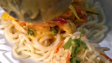 skilled chinese chef drizzles savory sauce over fresh udon noodles