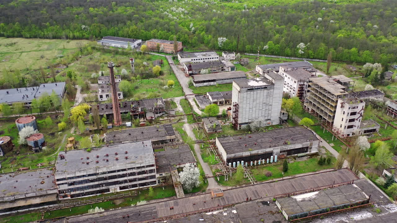 Abandoned factory industrial zone. Old factory warehouses. Ruined buildings on green nature background. Aerial drone view.