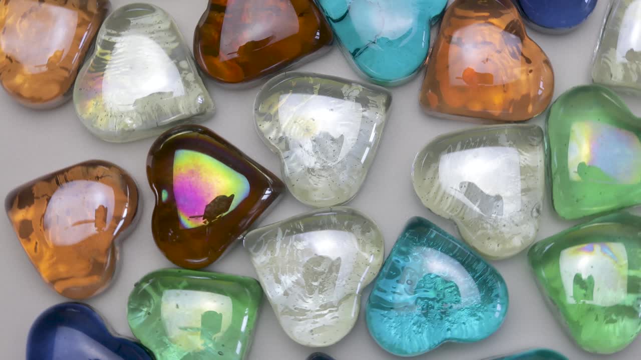 서로 다른 색의 유리 심장은 회색 배경에 원을 이루고 회전합니다.