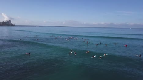 Una-Gran-Multitud-De-Surfistas-Esperando-Una-Ola-Sobre-El-Agua-En-La-Playa-De-Waikiki-En-Honolulu-Hawaii,-Cacerola-De-Camiones-Aéreos