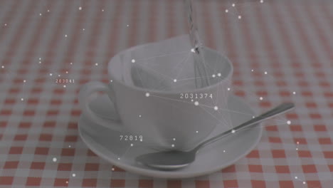 liquid pouring into ceramic cup on saucer over checkered cloth, network overlay mapping data nodes