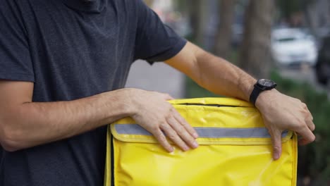 Cheerful-courier-zipping-yellow-backpack,-ready-to-deliver-order