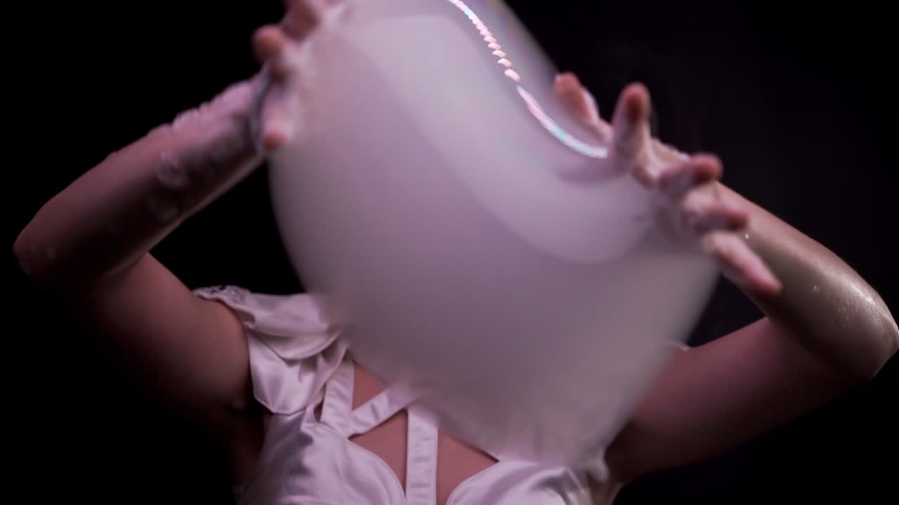 primer plano: la hembra hace trucos con burbujas de jabón, juega con burbullas, las tira con las manos