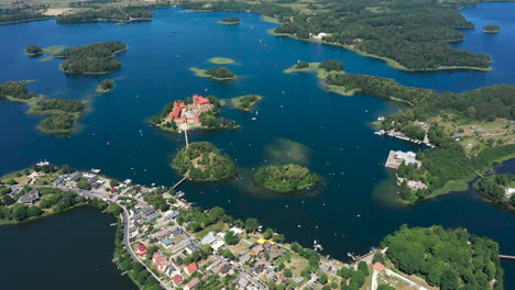antena: volando a gran altura sobre la ciudad de trakai con el castillo de la isla de trakai visible en el fondo rodeado por el lago y el bosque en el día brillante y soleado