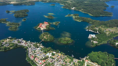 aerial: flying in very high altitude above trakai town with trakai island castle visible in the background surounded by lake and forest on the bright and sunny day