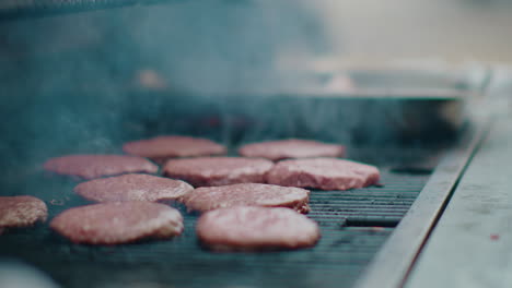 hamburgers smoking on an outdoor bbq grill, with fragrant smoke rising into the air. the camera slowly turns around the grill, showcasing the mouthwatering scene and vibrant grilling atmosphere.