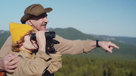 una pareja de ancianos haciendo senderismo y disfrutando de las vistas a las montañas.