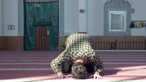 masked young man praying in mosque