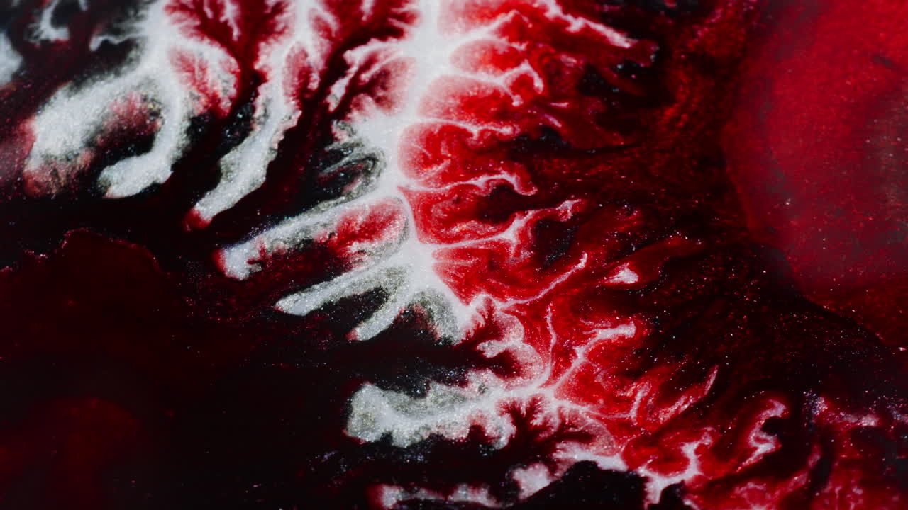 Ink in motion creating abstract mysterious red forms. Macro close up