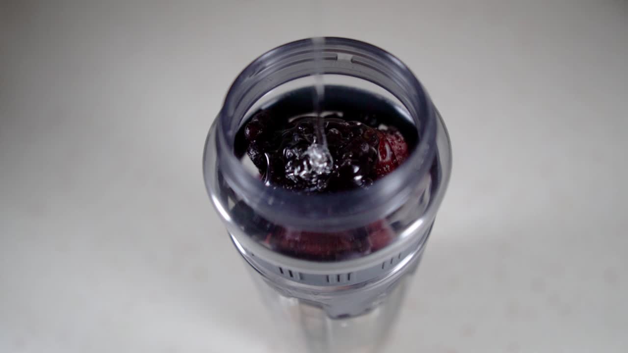 Pouring transparent syrup into a jar full of mixed berries, SLOW MOTION