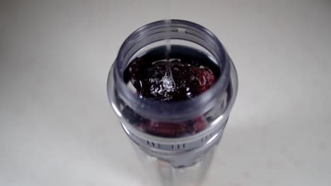 Pouring-transparent-syrup-into-a-jar-full-of-mixed-berries,-SLOW-MOTION