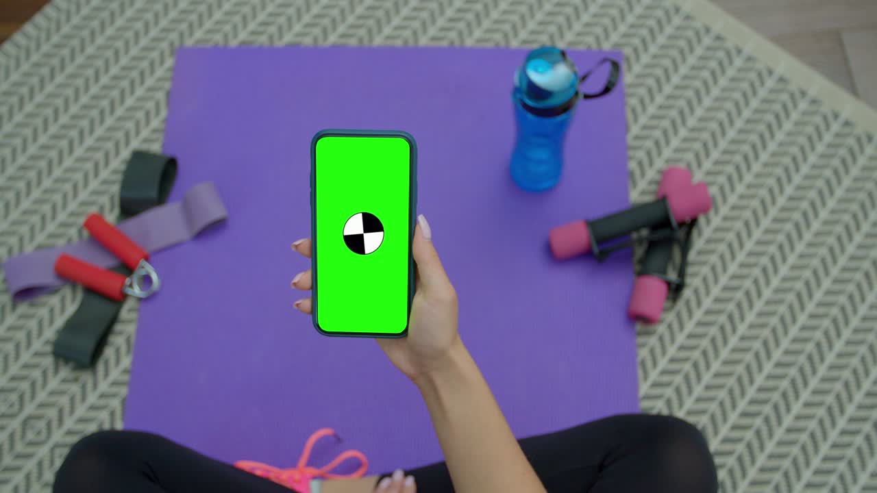 피트니스 여성은 집에서 훈련 한 후 녹색 화면으로 스마트폰을 사용합니다. 건강한 생활 방식. 스트레칭, 앞으로 기울어. 거리 훈련.