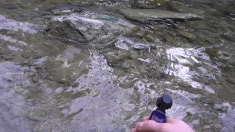 a filmmaker holds an action cam in his hands and captures footage of water from a swiss river