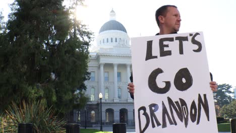 male political protester with let's go brandon sign slider dolly tracking shot