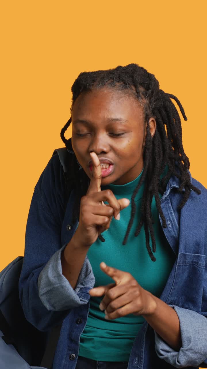 Jovem afro-americana pedindo silêncio com um gesto de "shhh"
