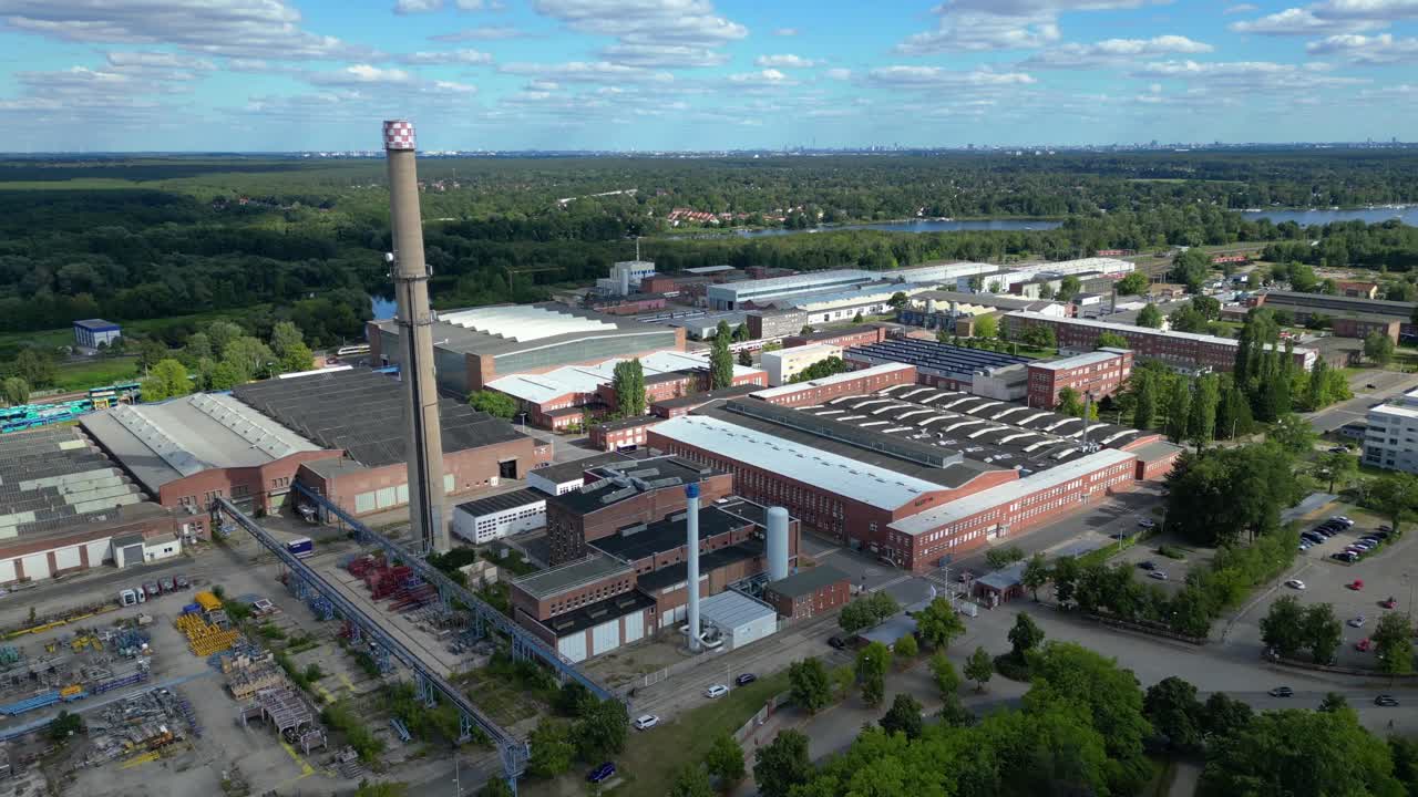 Hennigsdorf industrial area with modern offices, old factory buildings and chimneys under blue sky. Great aerial view flight fly push forward drone