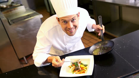 chef feliz vertiendo salsa en el plato de salmón