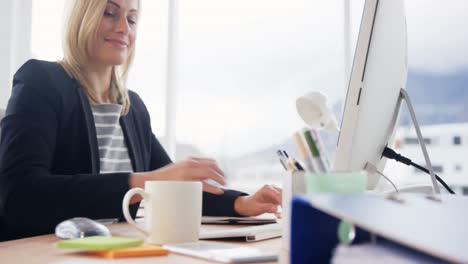 businesswoman drinking cup of coffee while working on computer