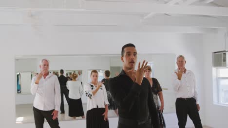 mixed-race-male-dance-teacher-taking-a-ballroom-dancing-class-at-a-dance-studio