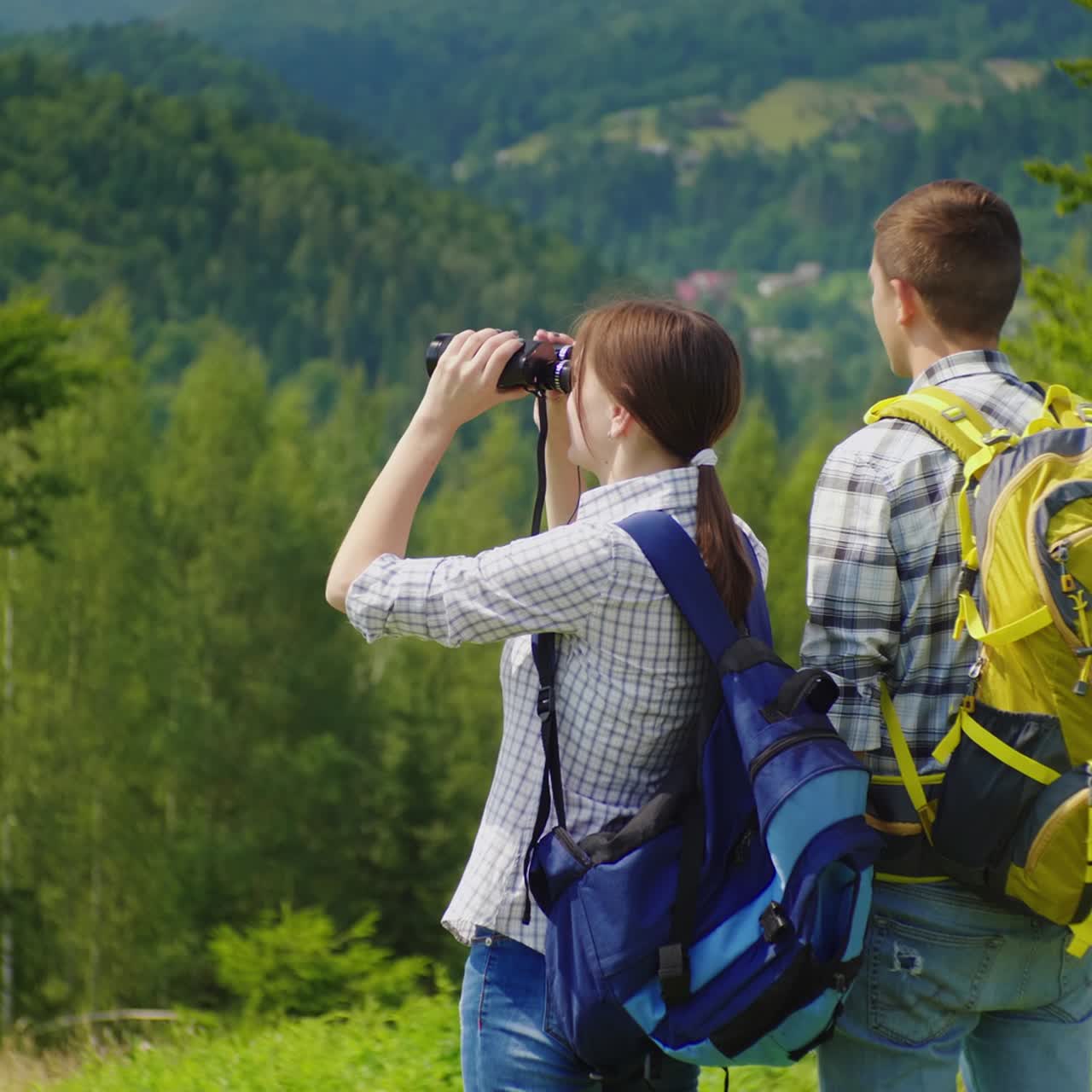 jóvenes turistas en el bosque mirando a través de binoculares 1
