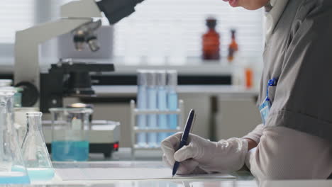 lab technician writing down chemical test results on paper