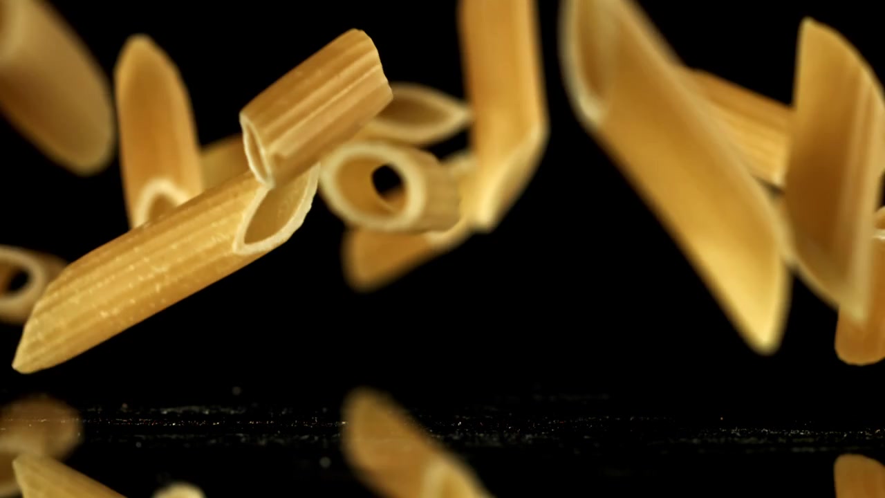 Penne dorate che cadono al rallentatore su uno sfondo nero
