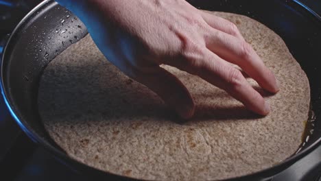 a bubbling closeup of egg, vegetables and cheese in a skillet, then a man's hand places a tortilla over the top