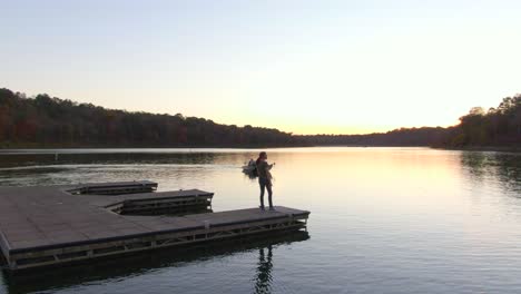 Umkreisen-Sie-Nach-Rechts-Ein-Mädchen,-Das-Bei-Sonnenuntergang-Am-Ende-Eines-Docks-Steht