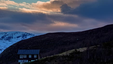 mountain chalet with a dramatic sunset cloudscape overhead - time lapse