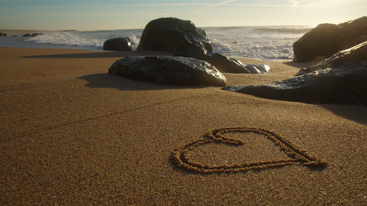 Heart draw in sand on beach at sunset. Romantic concept