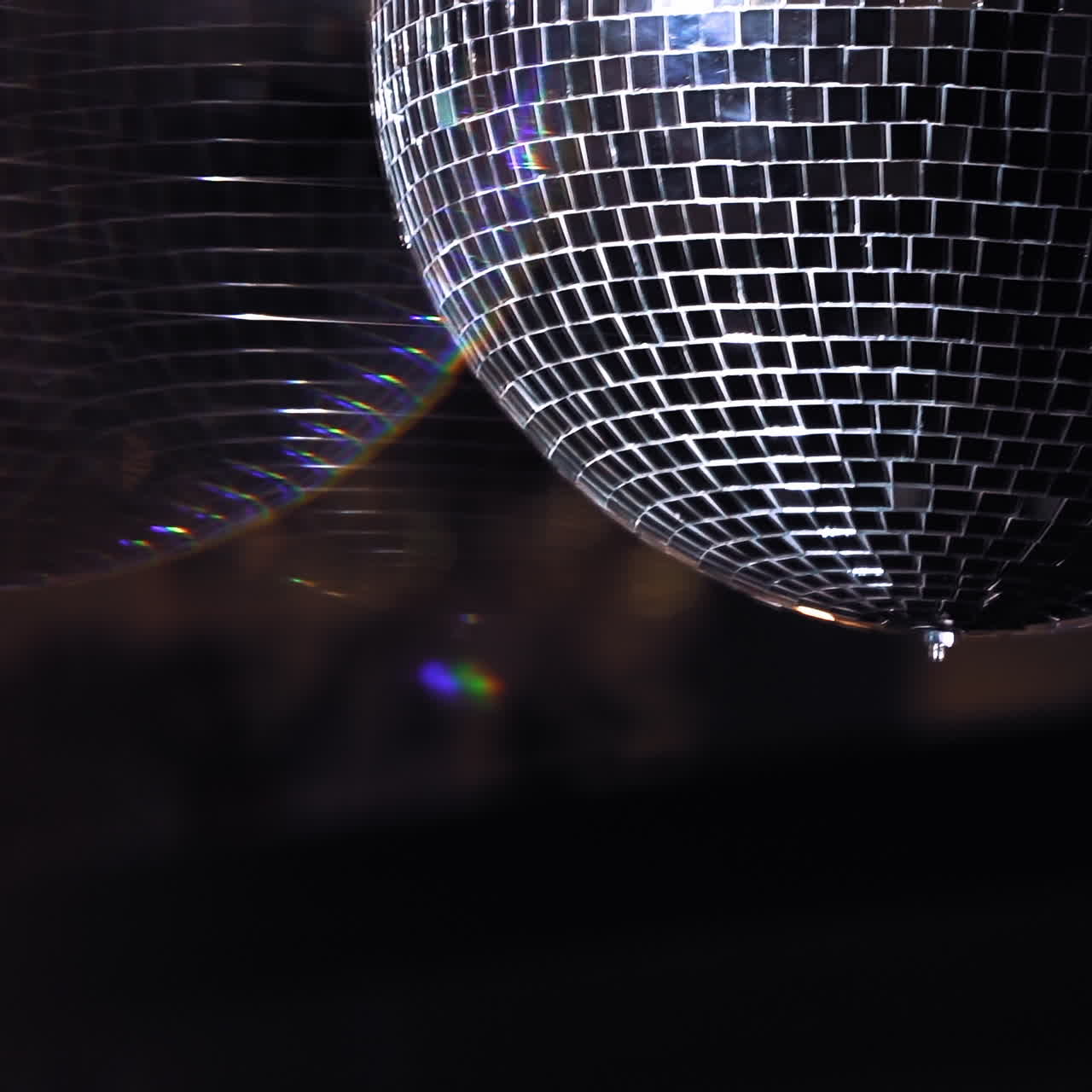 Mirror ball reflect rays of colored lights. Colorful reflective disco mirror ball with glinting highlights spinning slowly on a blurry background in disco club. The light show at night.