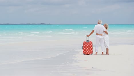 male female caucasian seniors on beach with suitcase