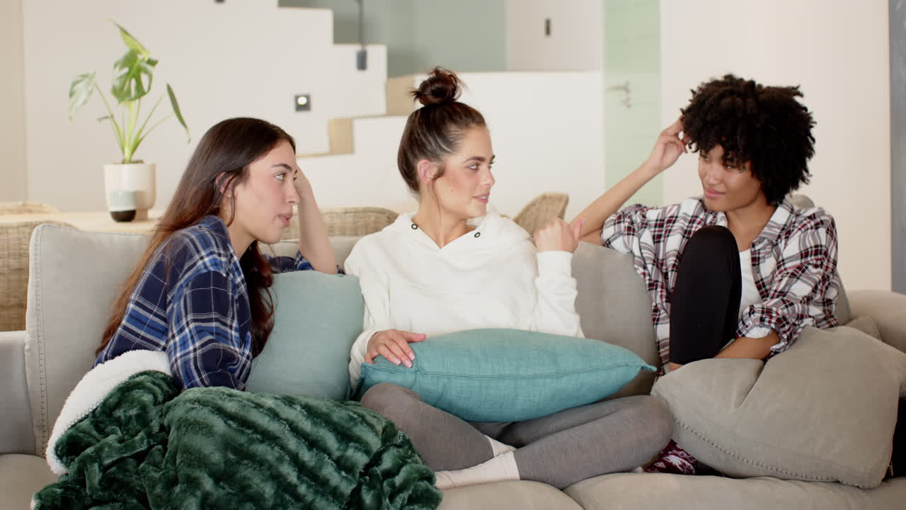 Women friends relaxing on cozy couch, enjoying conversation and laughter at home