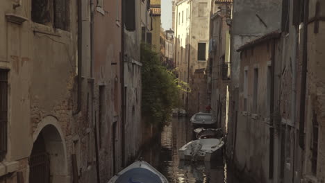 quiet narrow street with parked boats in venice, italy