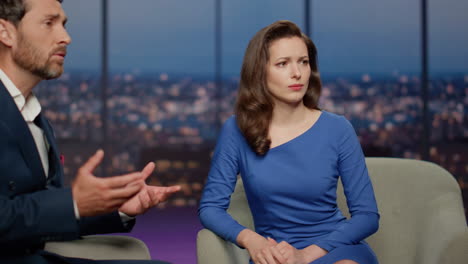 mujer corresponsal escuchando a un hombre en un programa de televisión.