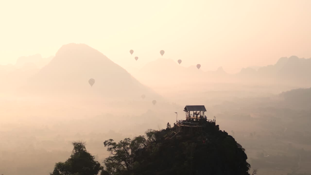 drone shot of viewpoint and hot air balloons during sunrise in Vang Vieng, the adventure capital of Laos