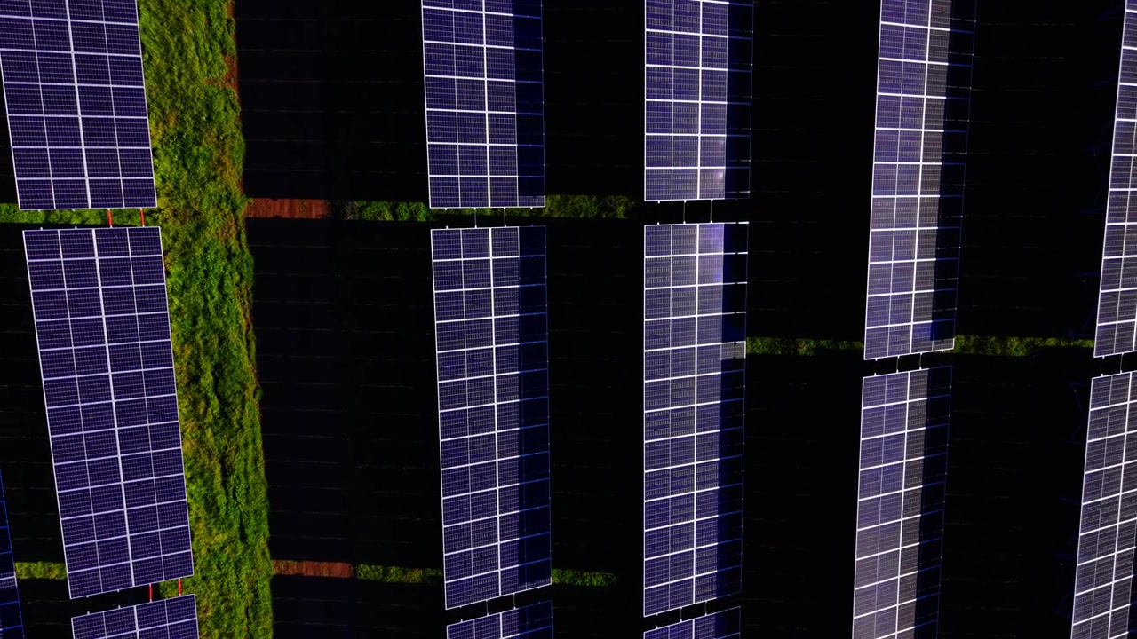 Luce su un impianto fotovoltaico. Ripresa ravvicinata dall'alto di alte colonne di pannelli con sottili riflessi viola e ombra scura. Vista aerea