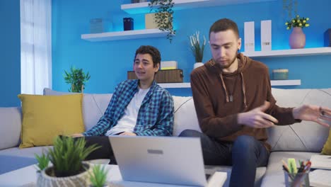 Young-man-studying-using-laptop-gets-angry-and-uncomfortable-with-his-younger-brother.