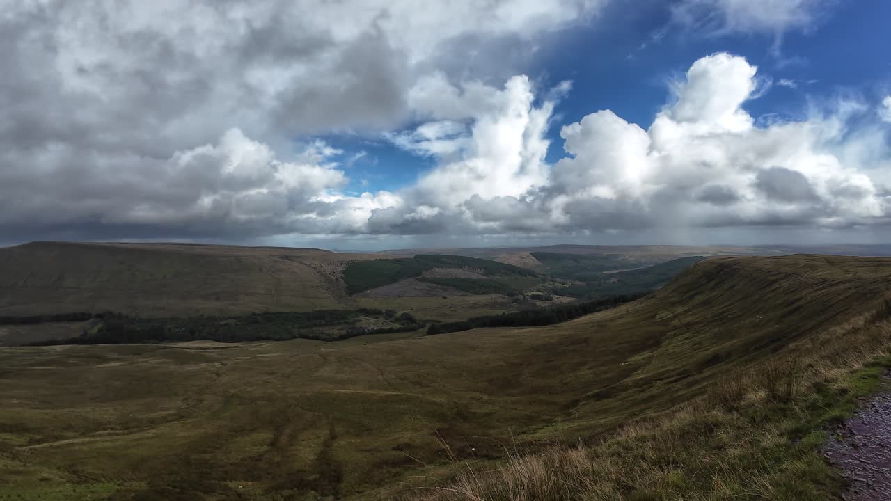 Expansive view across the Brecon Beacons National Park on the walk up to Pen y Fan, showcasing vast rolling hills, dramatic clouds, and sunlight breaking through over the scenic Welsh landscape