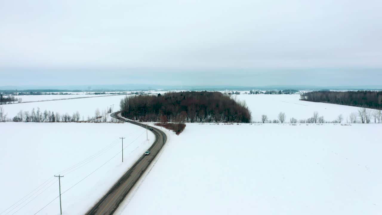 беспилотник пролетает и поднимается над проселочной дорогой зимой