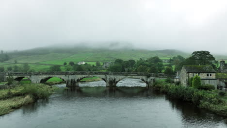 Slowly-tracking-forwards-over-water-towards-bridge-in-overcast,-Yorkshire,-United-Kingdom