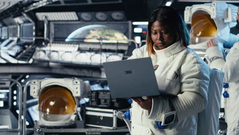 astronaut monitoring systems on laptop during human expansion in space