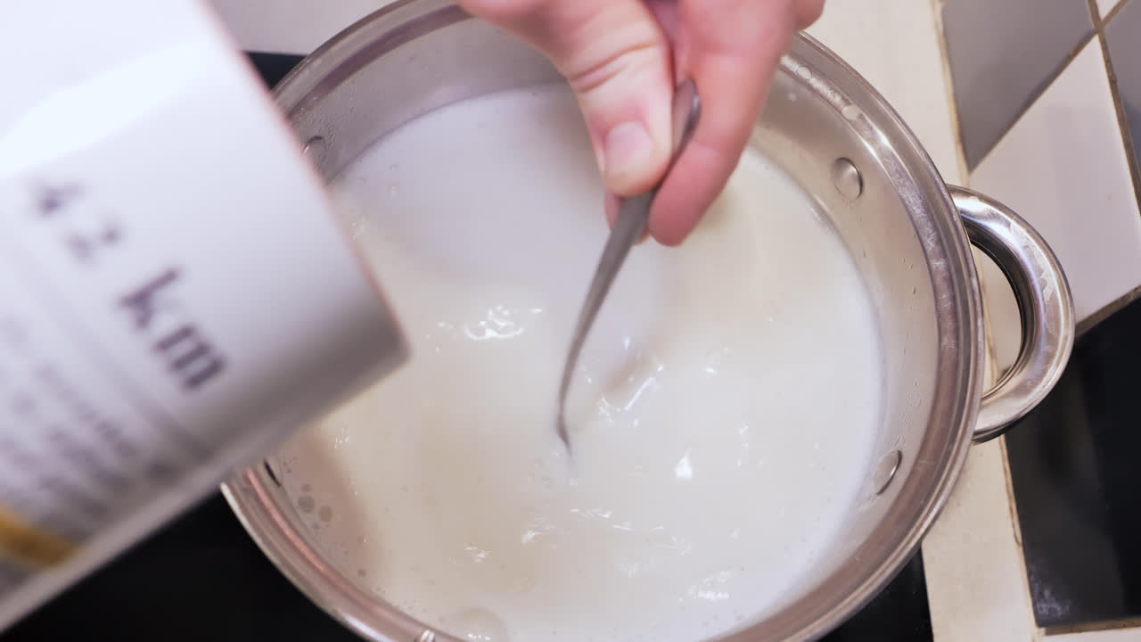 Slow motion pour of semolina into milk pot, a calm morning cooking routine