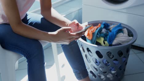 woman using mobile phone at laundromat 4k