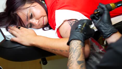 woman getting tattooed by professional artist in a studio. close-up handheld shot