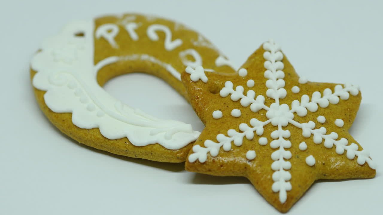 Zoomed in confectionery gingerbread with white decoration on top in the shape of a bell and horseshoe pf on a white background