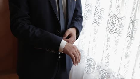 handsome groom fixes his jacket. wedding morning. businessman. slow motion