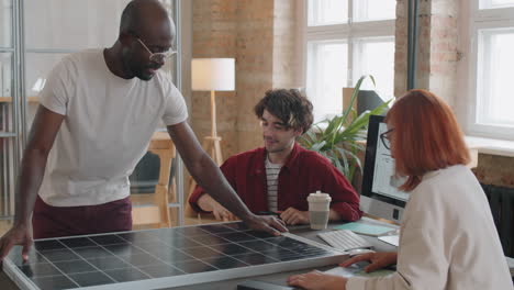 team of multiethnic engineers discussing solar panel in office