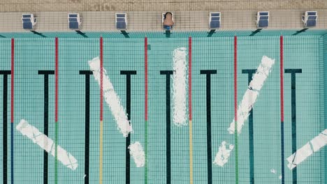 Top-shot-of-a-man-jumping-in-an-olympian-swimming-pool