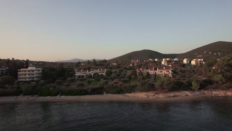 Aerial-scene-of-Trikorfo-Beach-shore-with-cottages-and-green-hills-Greece